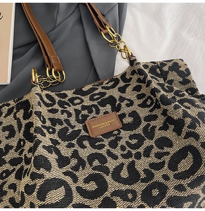 Close-up of leopard print tote bag fabric with leather logo patch and gold chain strap