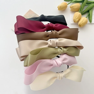 Set of seven satin bow headbands in assorted elegant colors on a white background