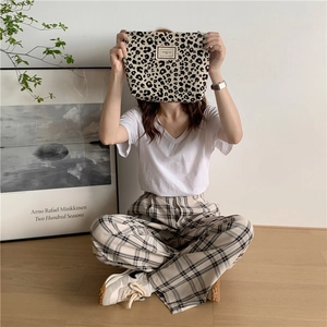 Detail of leopard print canvas clutch held by a model in a minimalist lifestyle setting
