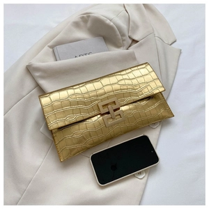 Minimalist gold crocodile-embossed clutch with geometric metal clasp on a beige blazer