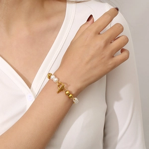 Close-up of pearl and gold bead bracelet with OT clasp on model's wrist