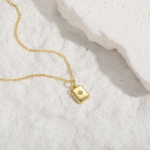 Macro detail of gold hexagram pendant with zircon inlay on a textured white stone base