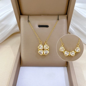 Detail of convertible gold clover necklace with heart crystals in premium jewelry box