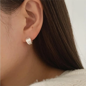 Close-up of minimalist sterling silver wavy hoop earring on female model ear