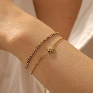Close-up of double-layer gold bracelets with star pendant and full crystal tennis chain