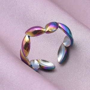 Macro detail of iridescent colorful steel ring on pink satin fabric background
