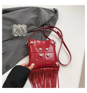 Macro shot of red crossbody bag with silver rivets and long fringe tassel details