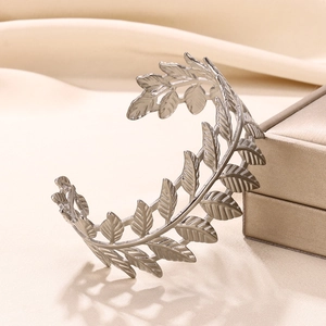 Macro shot of silver-colored leaf-shaped bangle with detailed vein texture on satin