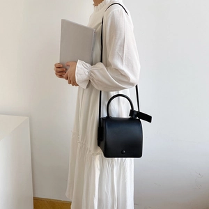 Minimalist black square crossbody bag for women with round handle and sleek surface
