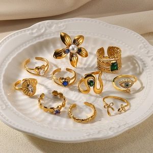 Set of 9 gold irregular rings featuring pearls and floral designs in a decorative tray