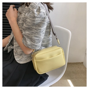 Détail d'un sac bandoulière en cuir grainé jaune clair avec sangle en tissu rayé
