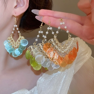 Close-up of bohemian tassel earrings with round shell sequins and gold pearl hooks
