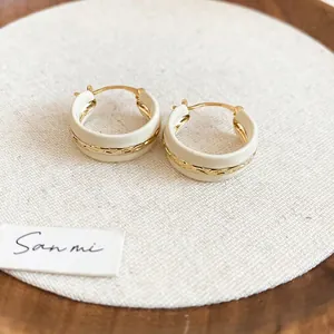 Detail of vintage enamel hoop earrings with gold twisted rope texture and cream finish