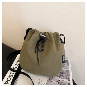 Close-up of olive green nylon drawstring bucket bag with black webbing strap details