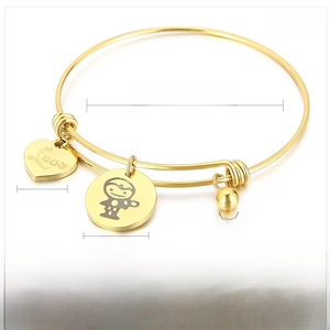 Detail view of gold stainless steel expandable bracelet with engraved heart and charms