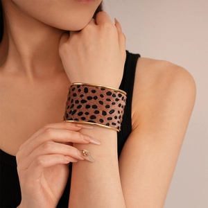 Close-up of leopard print velvet cuff bracelet with gold metal edges on a model's wrist