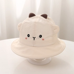Détail d'un chapeau de soleil pour bébé avec broderie animale et oreilles 3D sur tissu crème