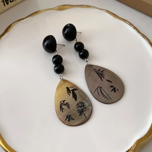 Dettaglio degli orecchini in madreperla con motivi di bambù e calligrafia cinese