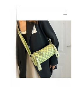 Detail of green checkerboard cylinder bag showing textured fabric and wide shoulder strap