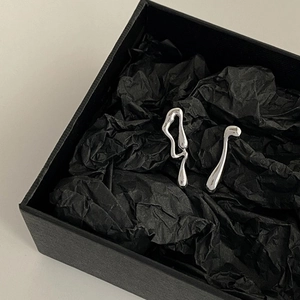 Minimalist silver asymmetric liquid lava stud earrings on a textured black jewelry box