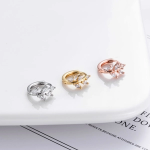 Detailed view of leaf-shaped ear hoops in silver, gold, and rose gold with inlaid zircons