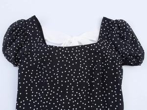 Close-up of black polka dot dress with square neck, puff sleeves and a back bow tie