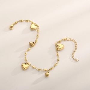 Close-up of a golden beaded anklet with heart-shaped pendants and lobster clasp closure