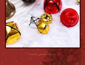 Macro view of colorful metal Christmas bells on white snow texture background
