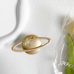 Detailed view of planet shaped gold phone grip with matte metallic finish and star design