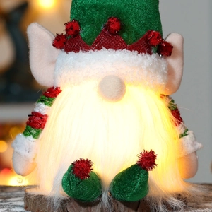 Close-up of a glowing Christmas gnome with green knit hat and warm LED light effect