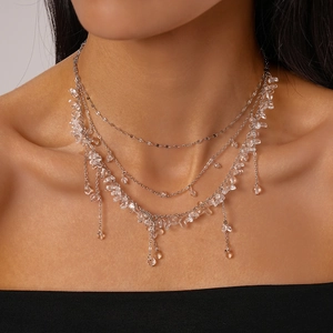 Detail of multi-layered silver necklace with irregular clear resin beads and fringe