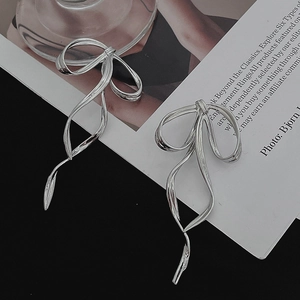 Artistic detail of long silver bow-knot streamer earrings with elegant metal texture