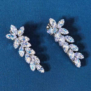 Detailed view of silver leaf hair clips with marquise crystals on a blue background