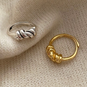 Detailed view of silver and gold knotted 925 sterling silver rings on knit fabric