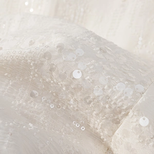 Macro del tessuto con paillettes bianche di lusso per un completo da donna elegante