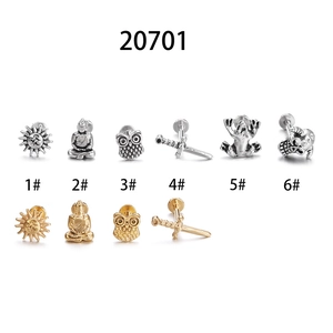 Flat lay of stainless steel frog and skull labret studs in silver and gold finishes