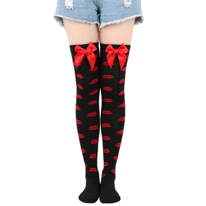 Detail of black over-the-knee socks with red lip patterns and cute decorative bows