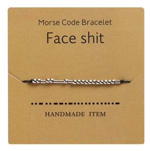 Macro detail of handmade Morse Code bracelet with silver beads on kraft paper card