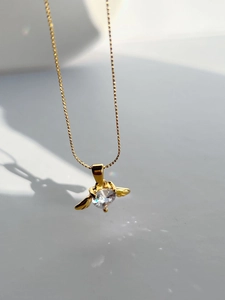 Detail of gold angel wing necklace with heart-shaped zircon and light reflection