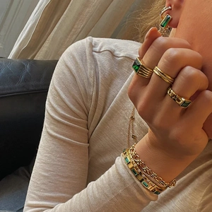 Detail of gold titanium steel jewelry set featuring vintage green zircon inlay on bracelets