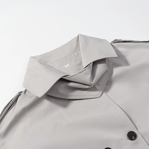 Detail of grey trench coat showing double collar design, shoulder epaulettes and resin button
