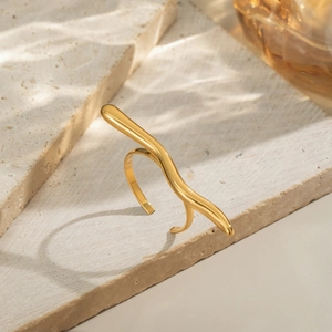 Macro detail of a golden organic wave ring on beige stone with water ripple lighting