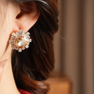Close-up of a model wearing vintage amber zircon earrings with gold plating details
