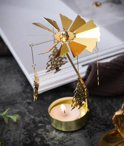 Detail view of a golden spinning carousel candle holder with Christmas tree pendants
