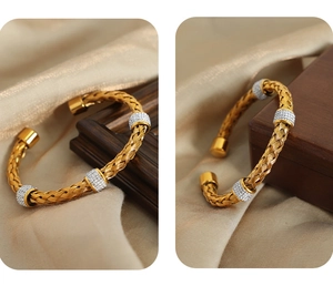 Detail of gold woven open bangle with silver rhinestone cylindrical charms on silk