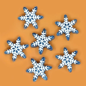 Flat lay of six blue glitter snowflake resin accessories for DIY Christmas crafts on orange