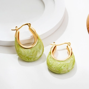 Macro detail of U-shaped gold earrings with light green marbled enamel inlay on white stand
