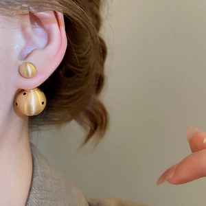 Macro detail of 18k gold plated earring with matte finish and black polka dots