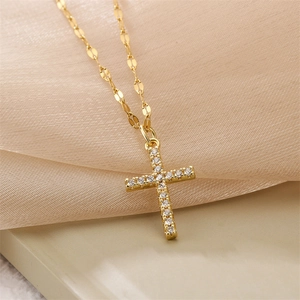Macro shot of gold cross pendant with cubic zirconia stones and flat oval link chain