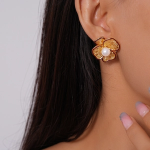 Detailed macro view of 18k gold plated hollow flower earrings with a centered pearl inlay